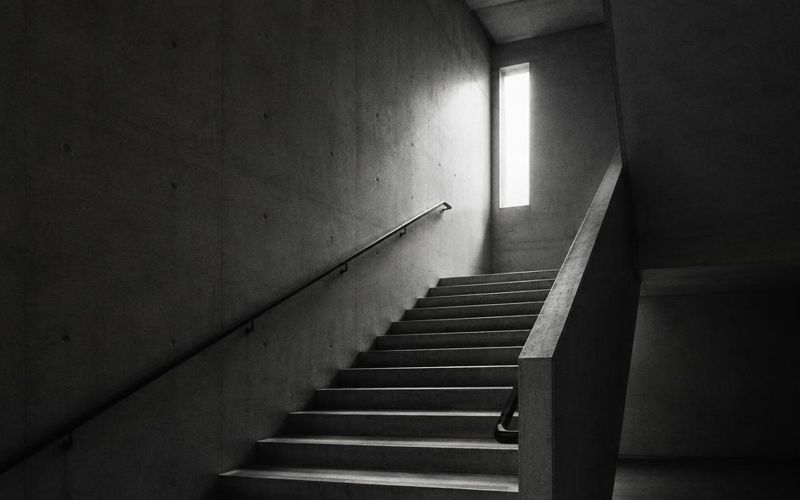 Concrete stairway rising toward a narrow window of light